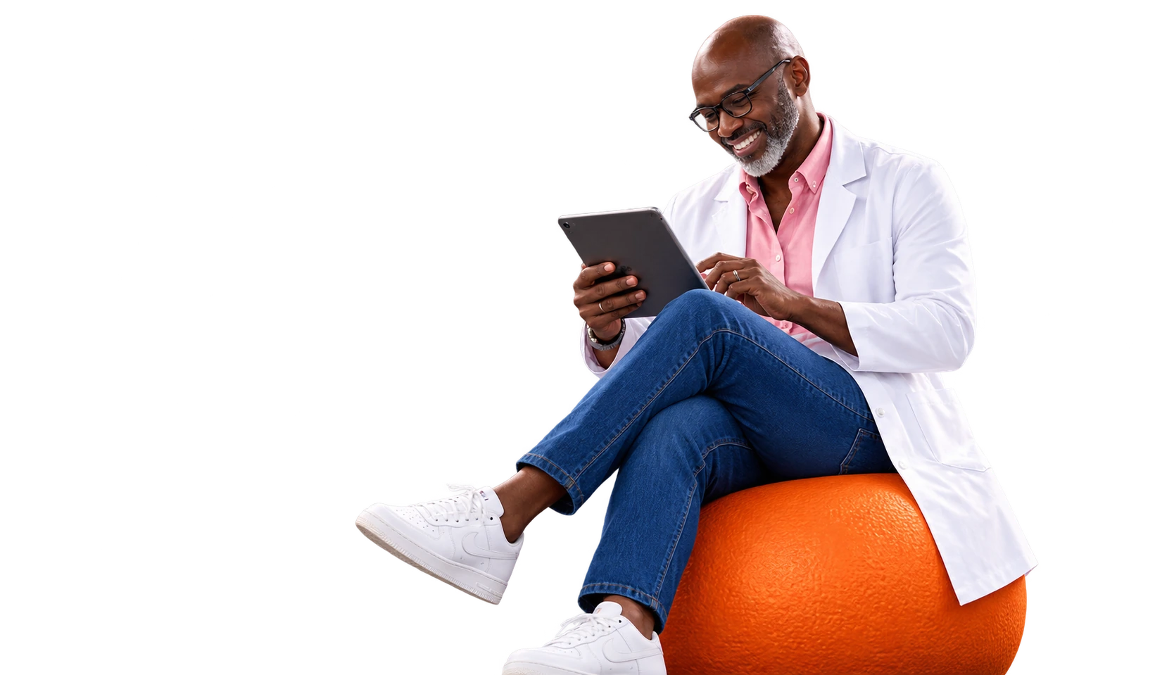 Médecin souriant consultant sa tablette, assis sur une sphère orange
